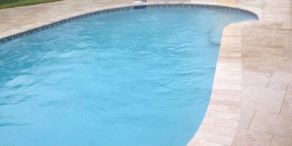 Pool deck after resurfacing, travertine pavers installed