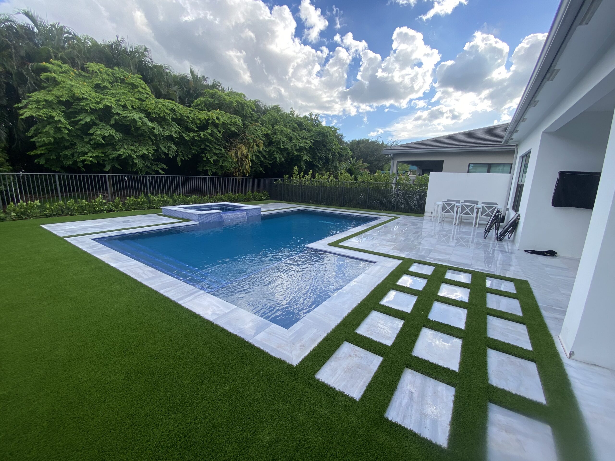 Modern rectangular pool with turf-and-paver deck design in Boca Raton, FL