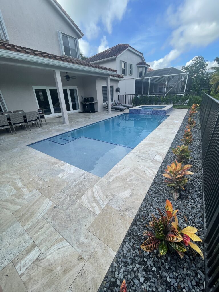 Rectangular pool with raised spa and travertine deck in Coral Springs, FL