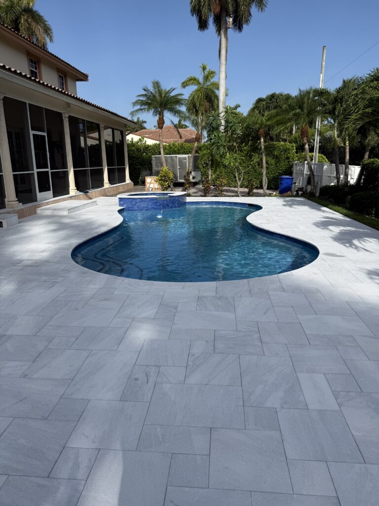 Kidney-shape pool with raised tile spa and screened lanai in Delray Beach, FL