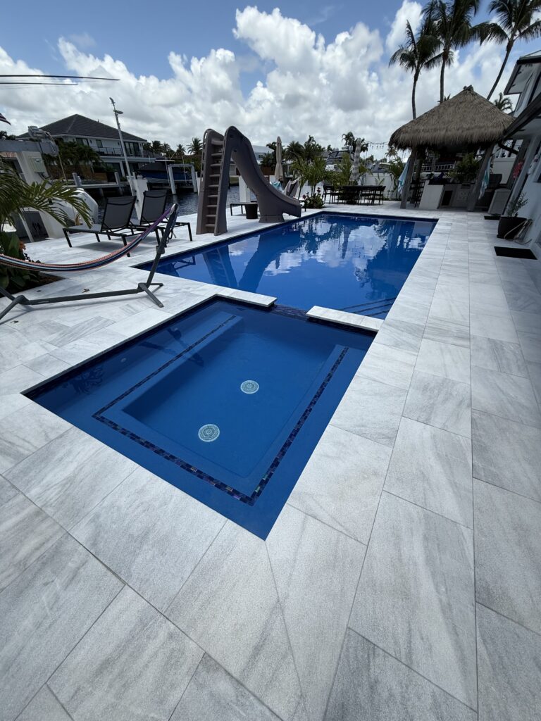 Pool with dark tile finish and raised spa, waterfront home in Fort Lauderdale, FL
