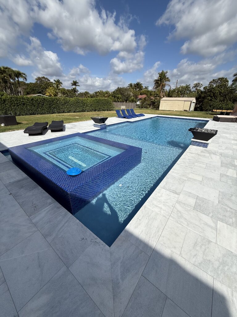 Pool with blue mosaic-tile raised spa and twin fire bowls in Lighthouse Point, FL
