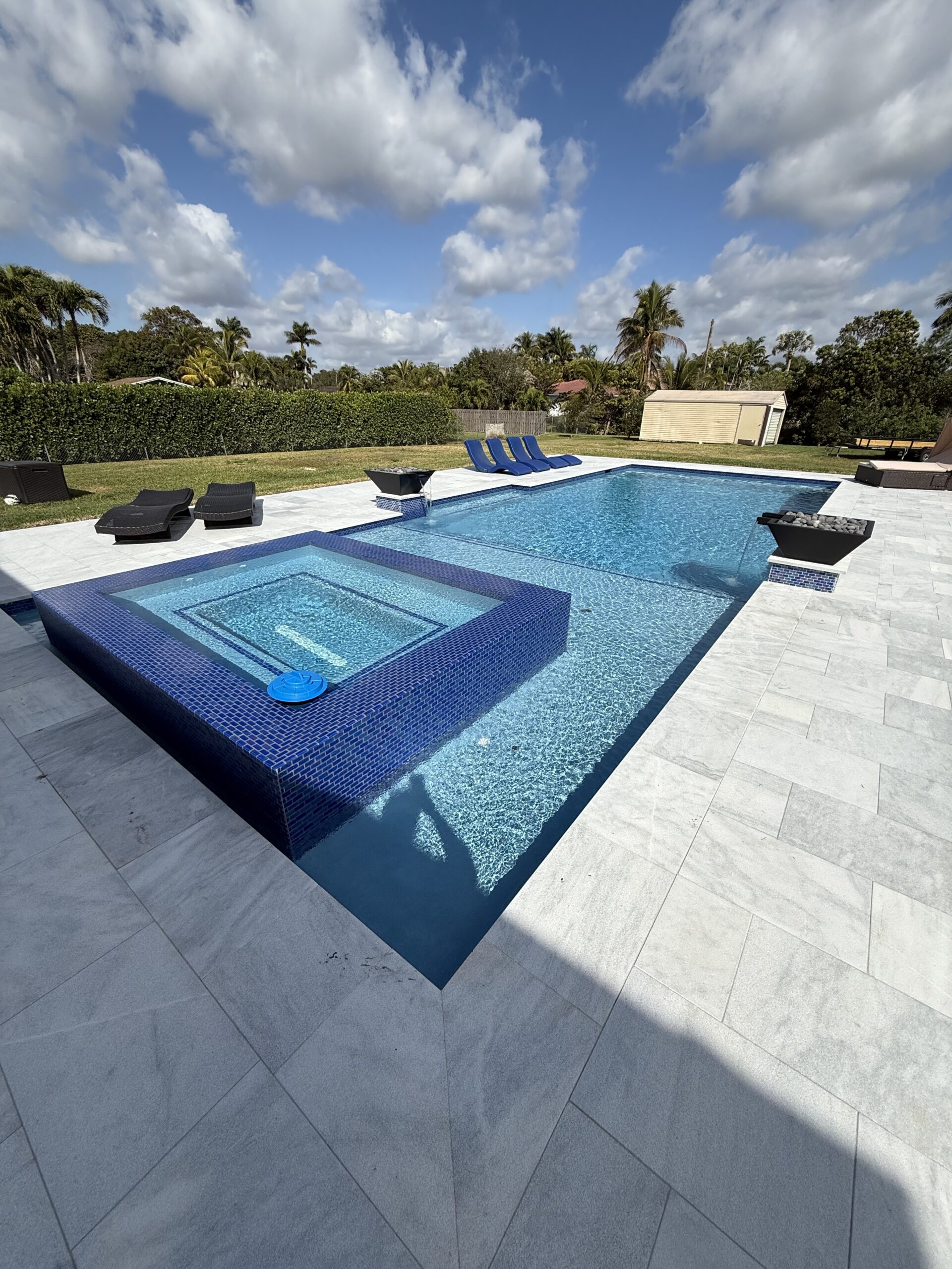 Pool with a blue mosaic-tile raised spa and twin fire bowls