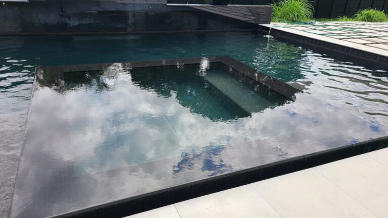 Traditional pool with raised spa, tile waterfall, and wood pergola dining area in Southwest Ranches, FL