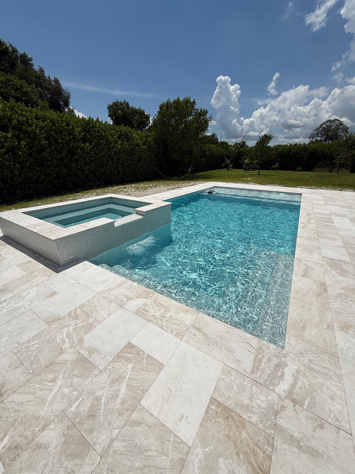 Finished rectangular pool with raised spa and sandblasted marble deck in Davie, Florida