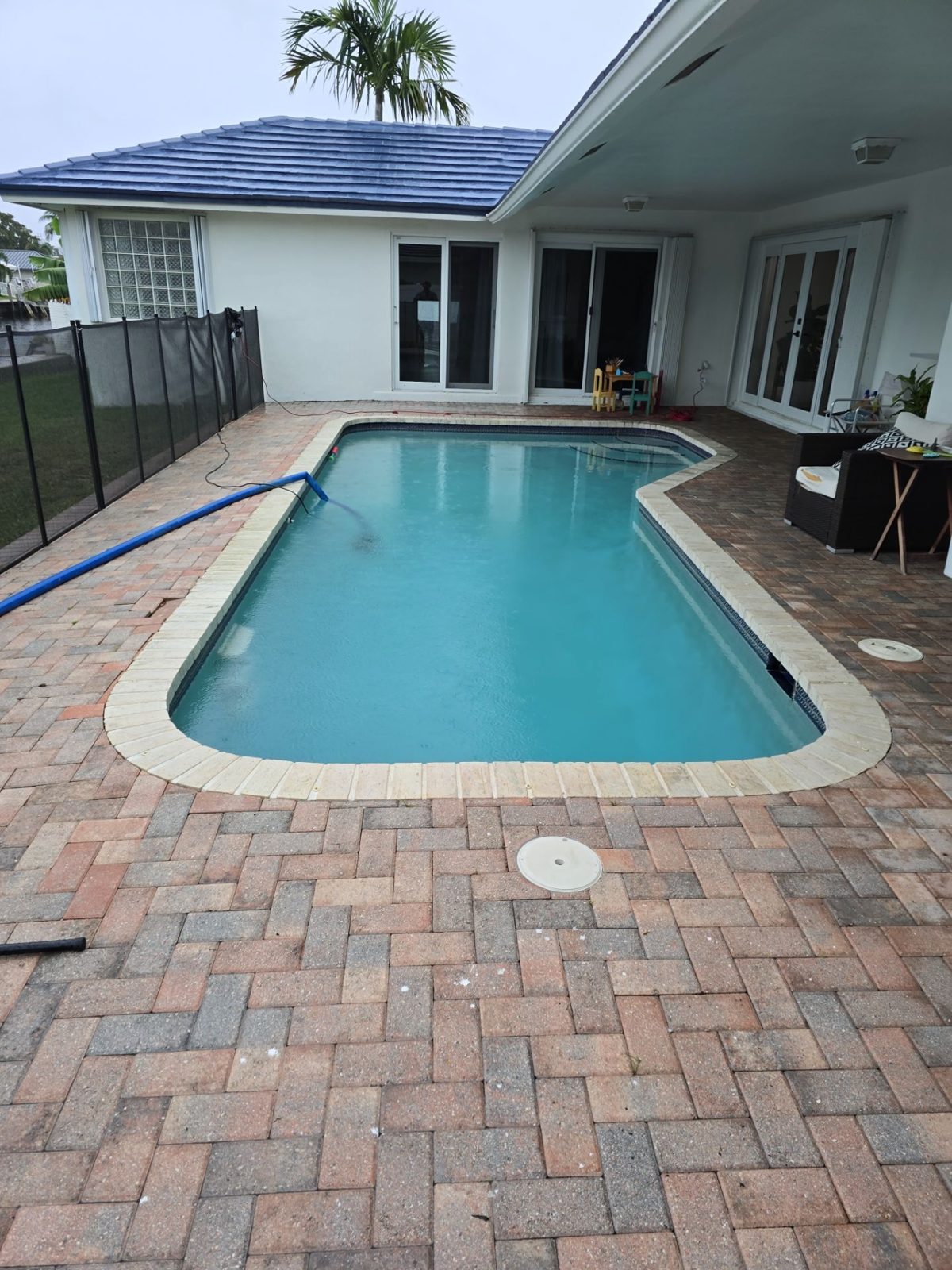Dated curved pool with brick paver deck in Fort Lauderdale before remodeling