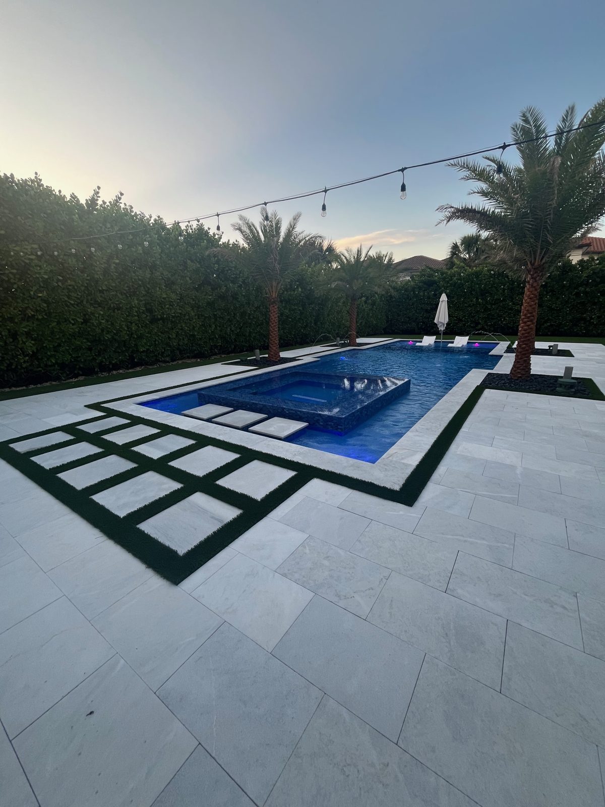 Modern Parkland pool at dusk with turf accents and marble decking