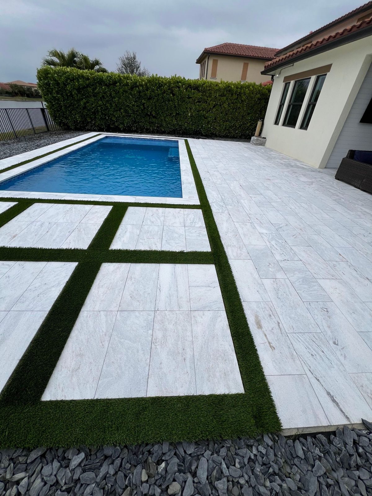 Modern rectangular pool with marble decking and turf inlays in Parkland, Florida