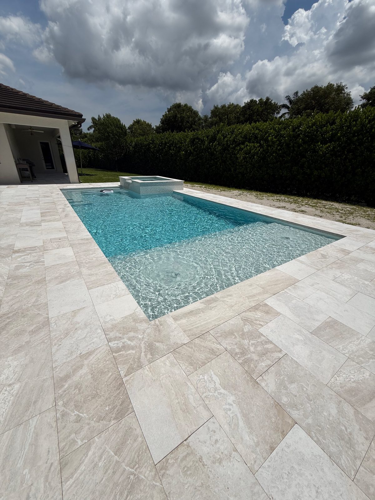 Sandblasted marble pool deck and spillover spa on a new pool build in Davie, Florida